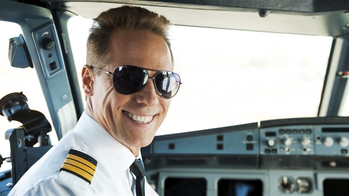 Pilot in cockpit. Rear view of confident male pilot looking over shoulder and smiling while sitting in cockpit 
