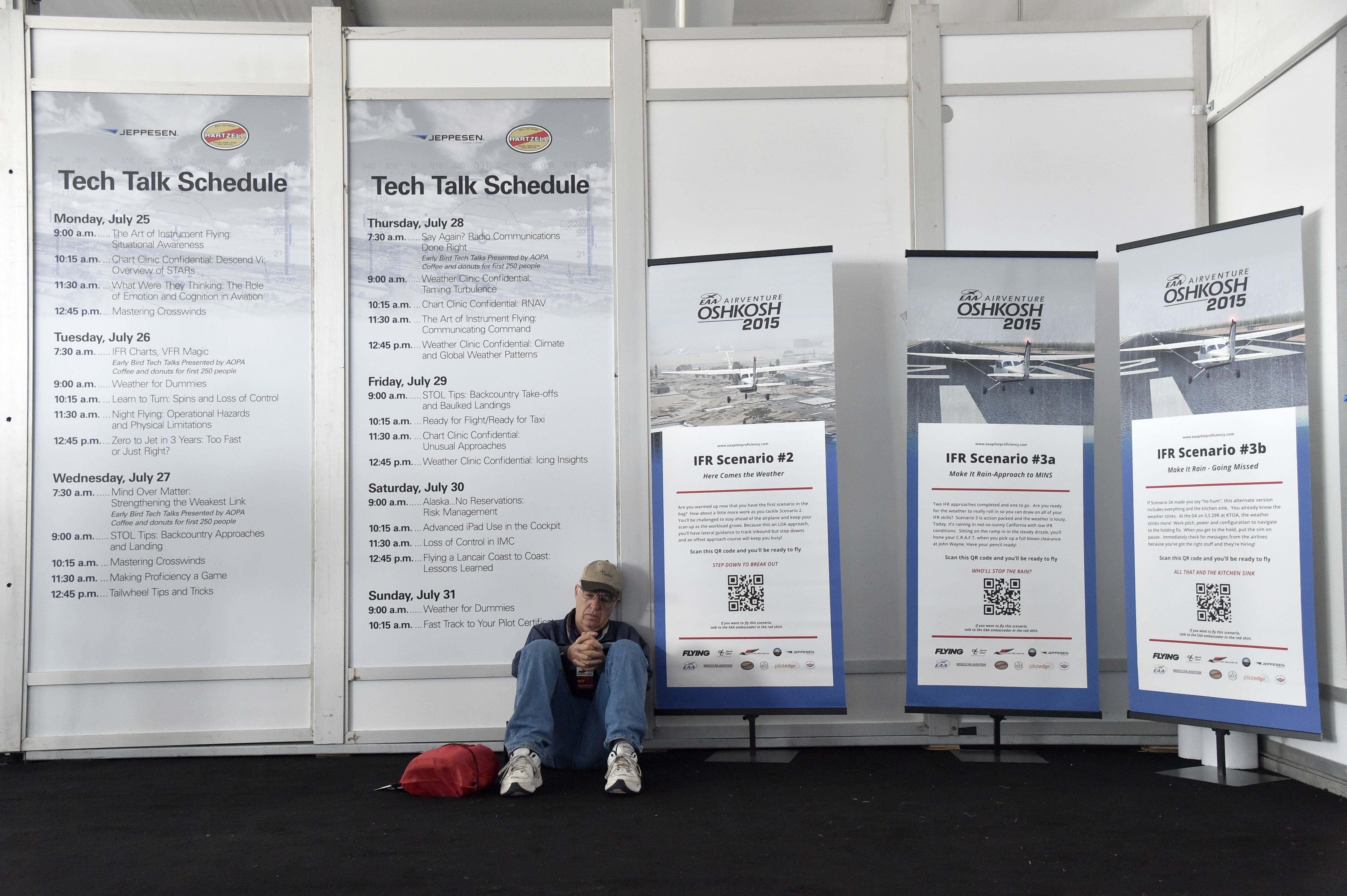 A pilot waits near Tech Talk posters in the Pilot Proficiency Center during EAA AirVenture. Photo by David Tulis.