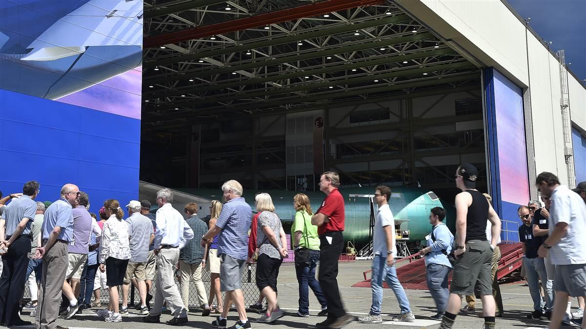A Boeing 747 under construction in a cavernous hangar frames attendees at Paine Field in Everett, Washington, during in a special VIP tour for the AOPA Fly-In at Bremerton, Washington, Aug. 19. Photo by David Tulis.
