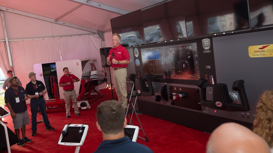Redbird Flight Simulations Founder Jerry Gregoire speaks July 24 at the company tent at EAA AirVenture. The giant flight simulator behind him was not designed to be functional, but to start conversations. Jim Moore photo. 
