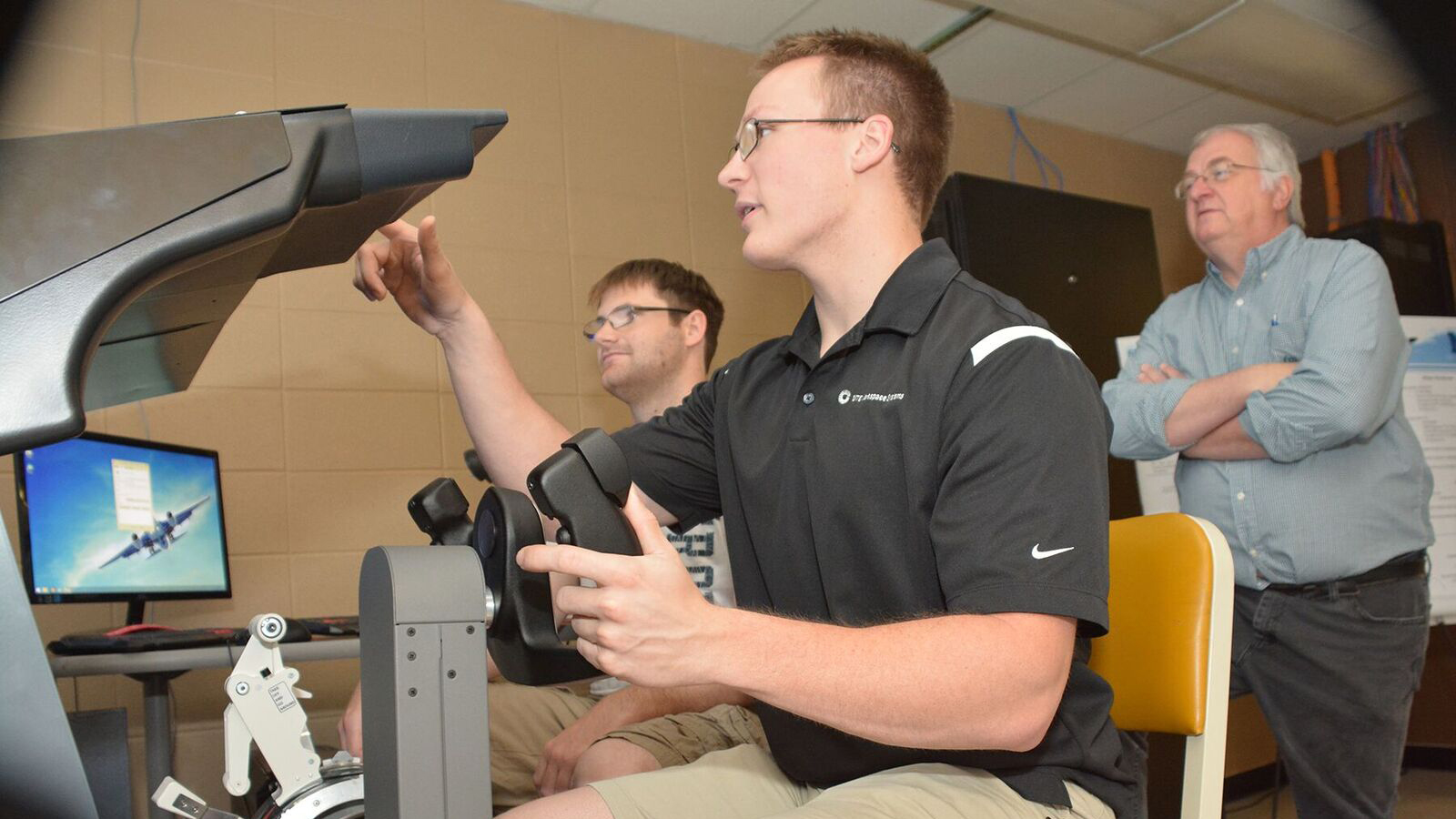 Sam Coffin, senior, electrical engineering major from Billings, Montana (left); Ted Schoper, junior, electrical engineering major from Baudette, Minnesota; and Scott Rausch, interim head of the Department of Electrical & Computer Engineering at the South Dakota School of Mines & Technology, at the flight simulator designed and built by students. Photo courtesy of Fran LeFort.