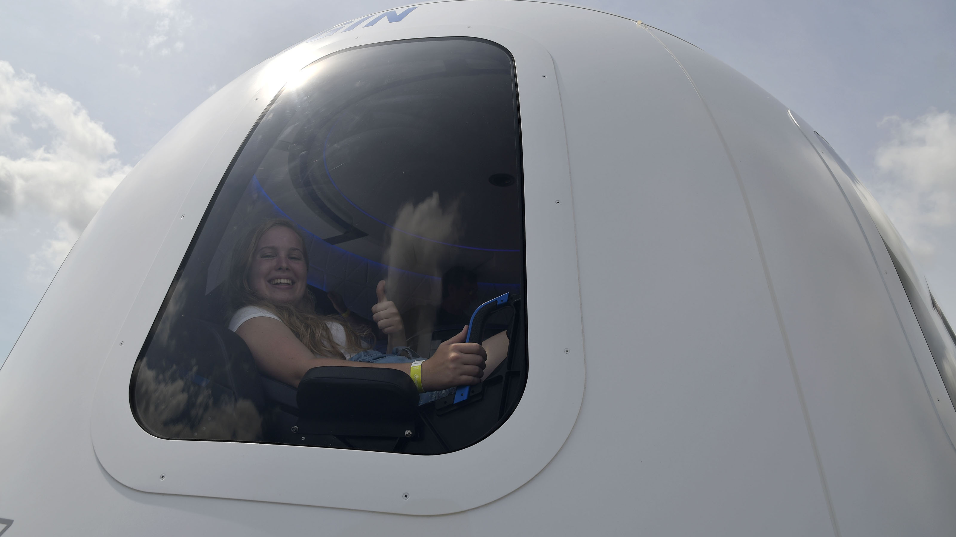 EAA AirVenture attendees experience what it's like to be an astronaut inside the Blue Origin space capsule mockup on display at Boeing Square in Oshkosh, Wisconsin. Photo by David Tulis.