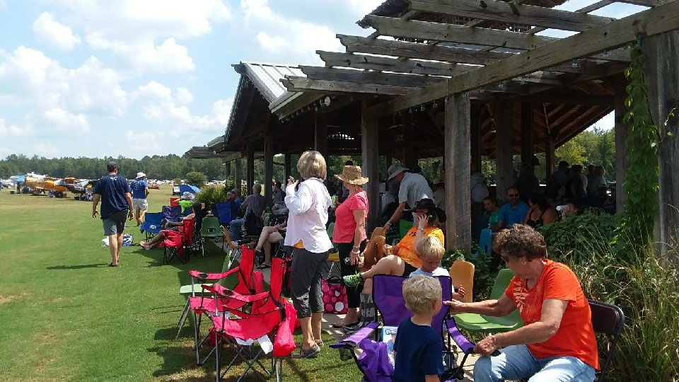 Until the total eclipse arrives over Triple Tree, spectators line up in the pilot lounge pavilion to snag some shade and watch the other main event--pilots' approach and landing at the 7,000-foot-long manicured turf strip. Photo by Alyssa Cobb.