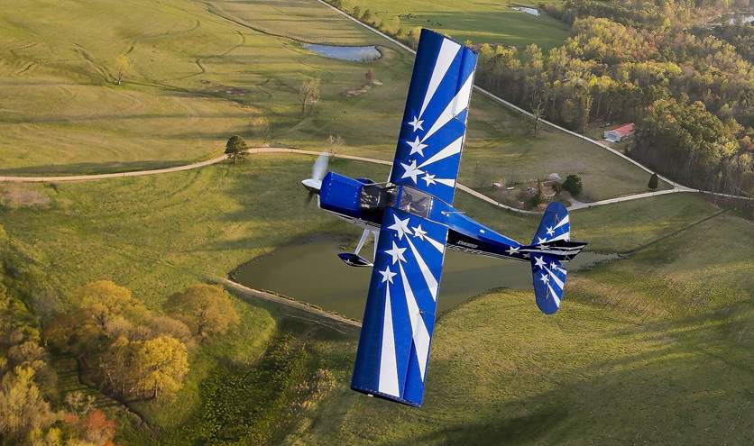 An American Champion Xtreme is in flight over the countryside. Photo by Chris Rose.         