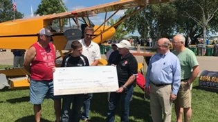 AOPA President Mark Baker presents AOPA Foundation Flight Training scholarship recipient Chase Harting with a $5,000 check during EAA AirVenture in Oshkosh, Wisconsin.