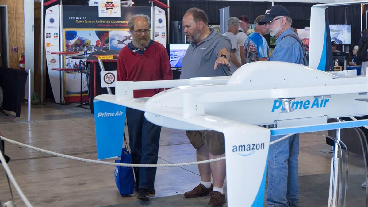 Amazon Prime Air Director of Manufacturing, Integration & Optimization Russell Williams (center, gray shirt) chats with a visitor to the company display at EAA AirVenture July 28. Jim Moore photo.