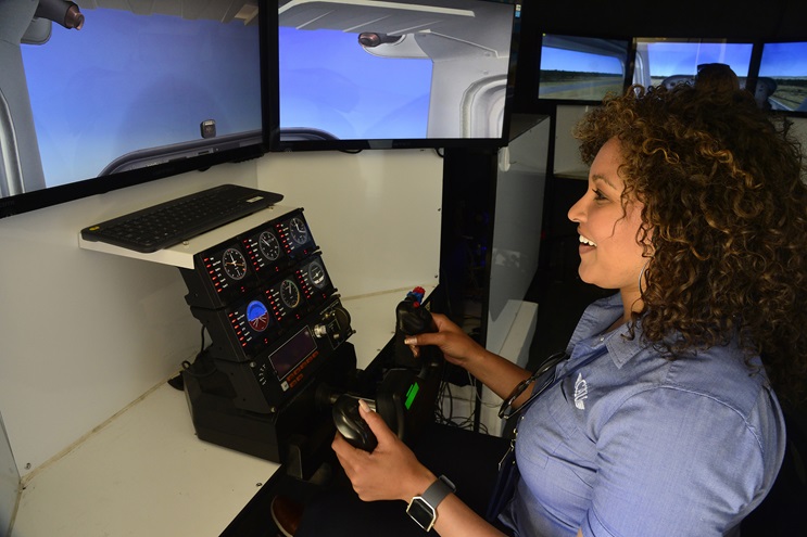 California Aeronautical University's Adia Smith tries her hand at a flight simulator inside the school's traveling classroom during the AOPA Fly-In at Camarillo, California. Photo by David Tulis.                   