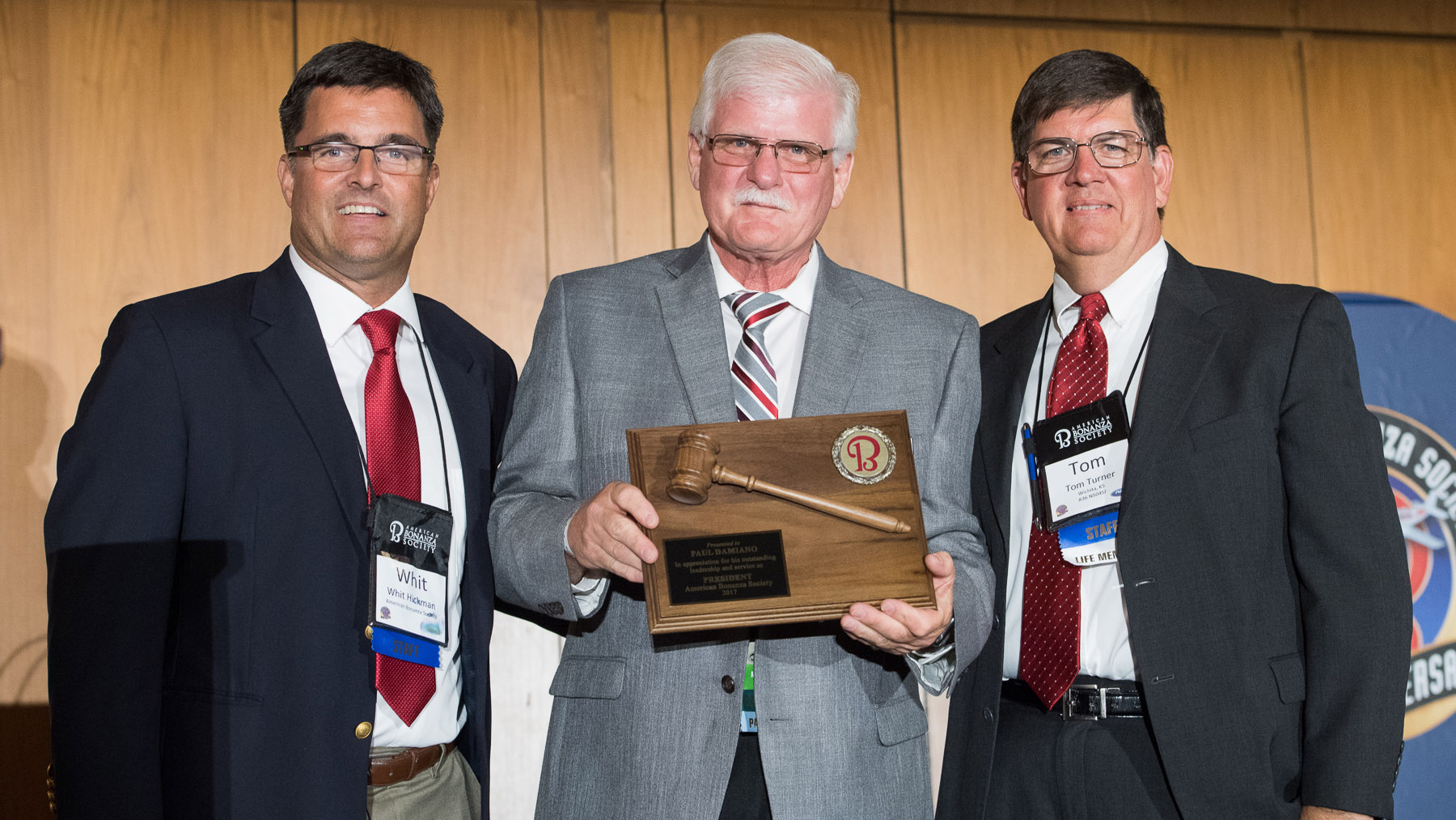 American Bonanza Society Executive Director Whit Hickman (left) and ABS Air Safety Foundation Executive Director Tom Turner (right) recognize the work of outgoing President Paul Damiano during the type club's fiftieth anniversary convention in Wichita. Photo courtesy of Visual Media Group.