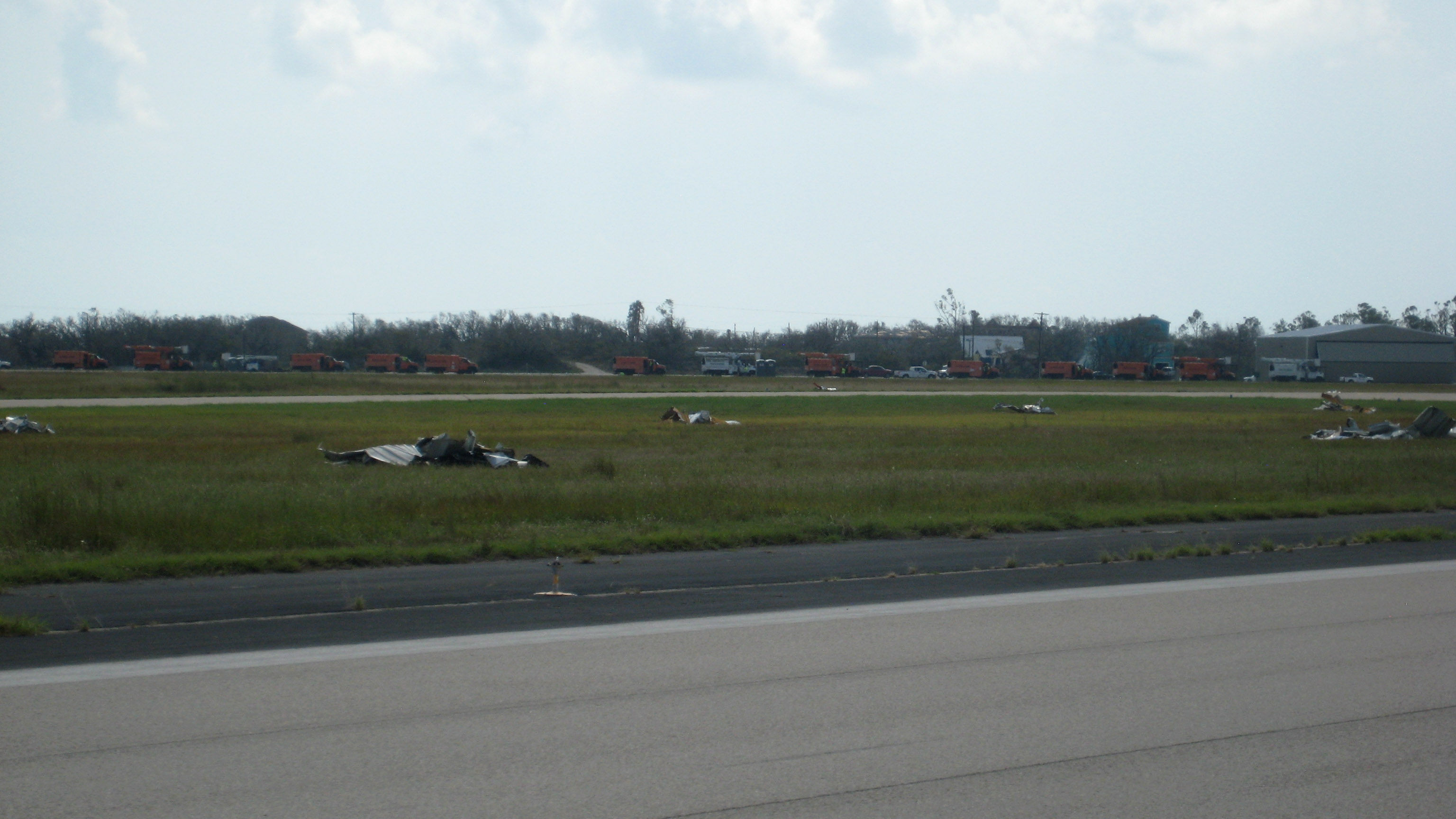 In Rockport, Texas, volunteers swept up piles of hangar debris. Orange FEMA trucks are in the background on the second runway. Photo by Larry Brown.