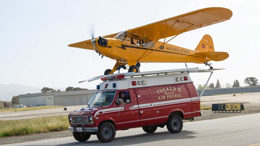Justin Ramsier drives a 1990 ambulance while Eric Tucker pilots his J-3 Cub from a platform attached to the ambulance roof. Photo courtesy of Method Seven and Donald Beirdneau.