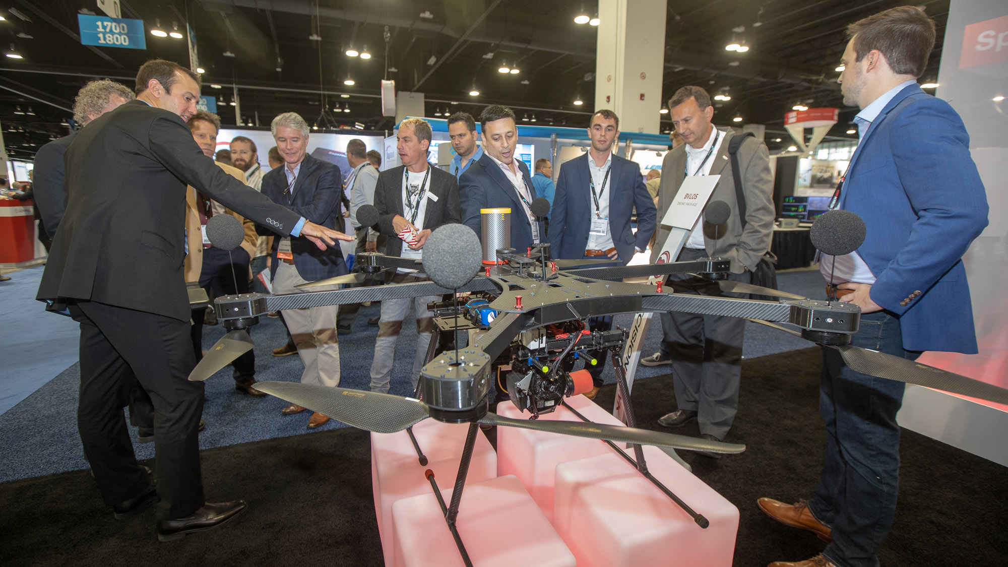 PrecisionHawk CEO Michael Chasen (center) briefs visitors about the company's efforts to facilitate drone flight beyond visual line of sight with an acoustic detection system to allow the drone to automatically avoid manned aircraft. Microphones mounted on top of the motors are part of this system. Photo by Jim Moore.