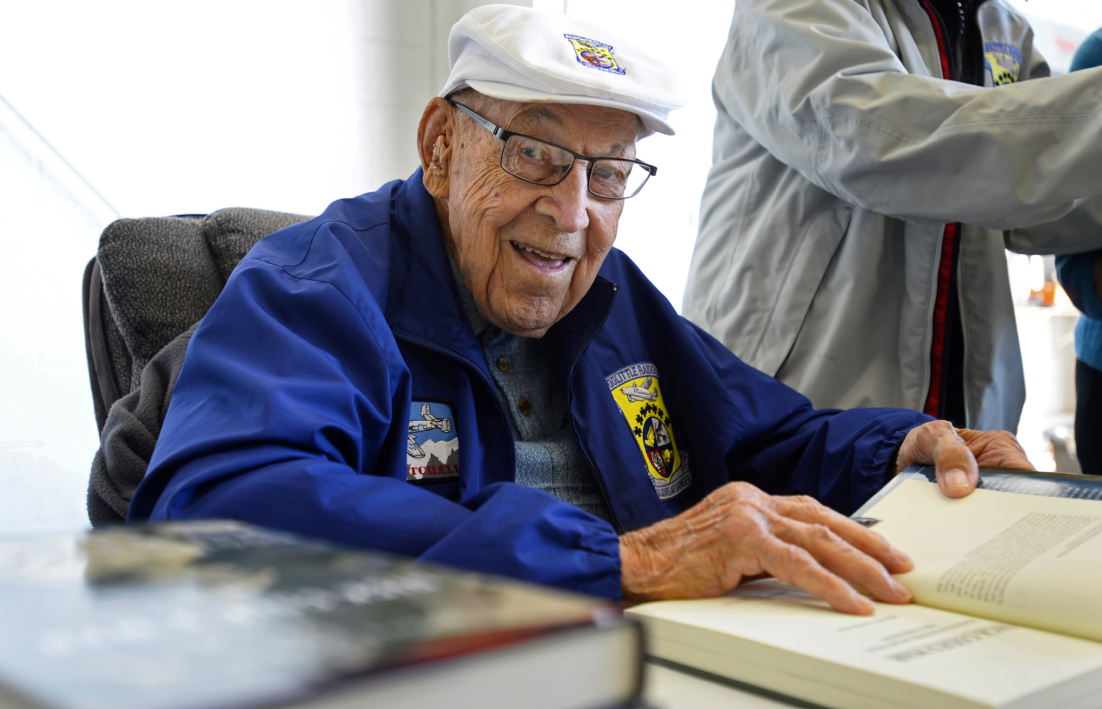 Retired U.S. Air Force Lt. Col. Dick Cole, who was known for his World War II role as a Doolittle Raider, autographs books during a 2015 AOPA visit. Cole died in April at age 103. Photo by David Tulis.