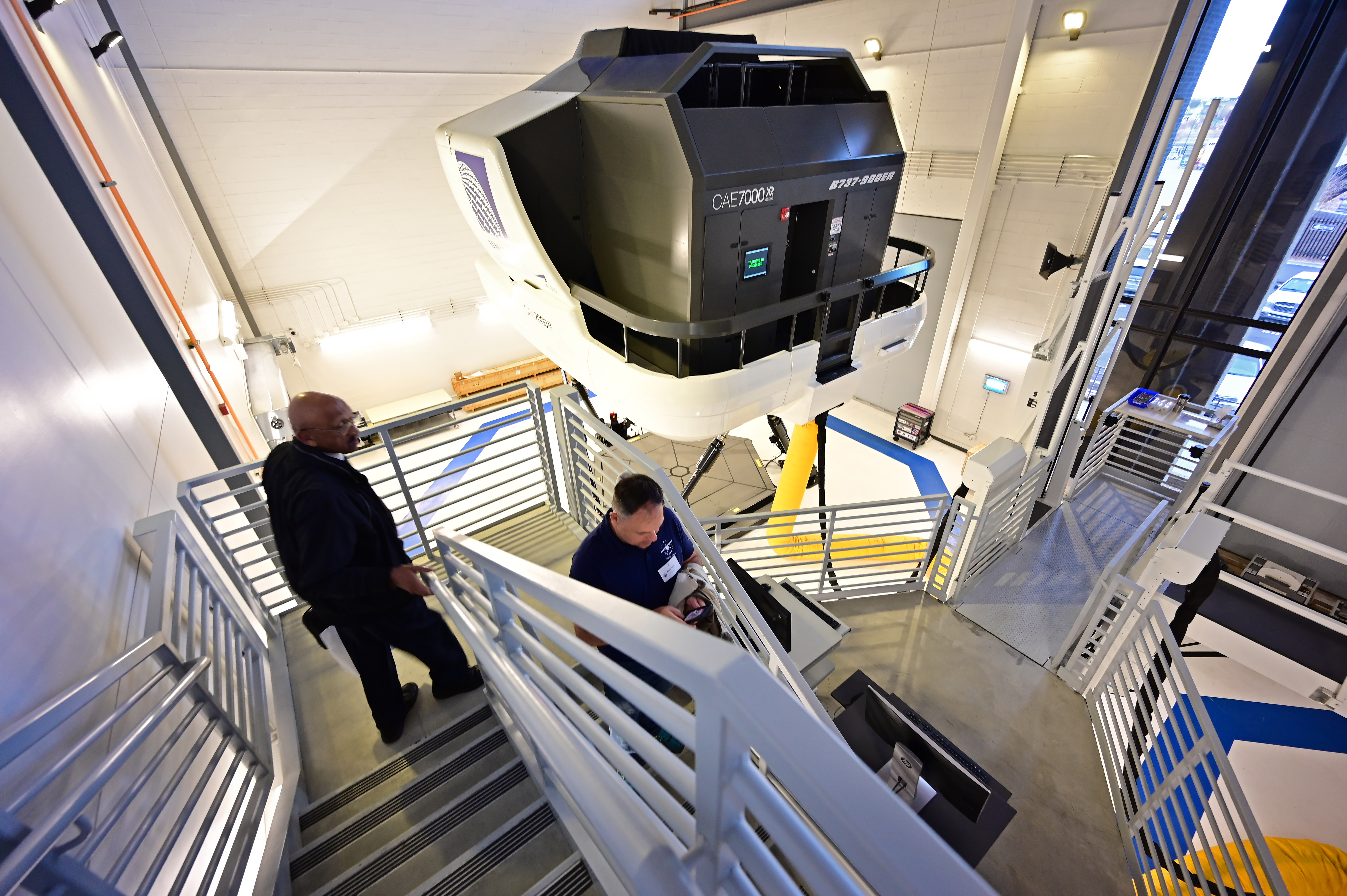 Retired U.S. Marine helicopter pilot and high school aviation teacher Kevin Moss, right, leads retired airline Capt. Warren Wheeler to full-motion Boeing 737 flight simulators. Photo by David Tulis.