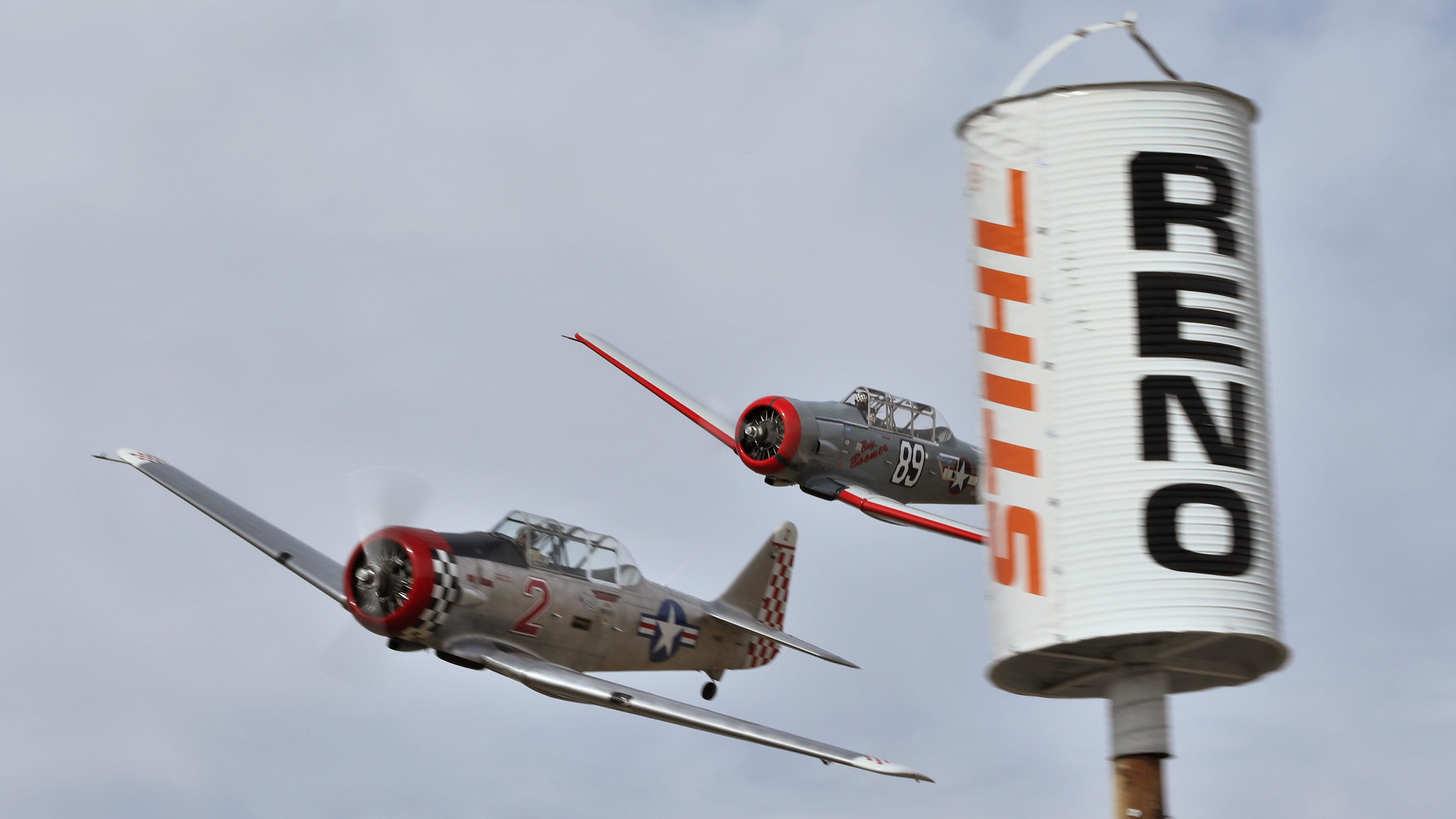 Harvard MK IV "Bare Essentials," flown by Michael Pfleger, left, battles with Gene McNeely's AT-6, "Baby Boomer," going around a pylon at the 2019 Stihl National Championship Air Races. Photo by Robert Fisher.