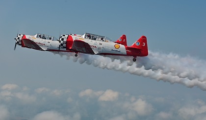 "Smoke on!" AeroShell Aerobatic Team pilots Steve Gustafson and Bryan Regan fly North American T-6 Texans in formation during EAA AirVenture in Oshkosh, Wisconsin. Photo by David Tulis.