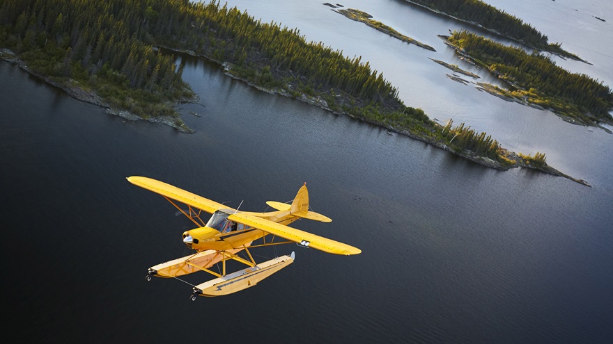 A Super Cub on floats flying over Gods Lake near the Elk Island Lodge in Manitoba, Canada. Photo by Mike Fizer.