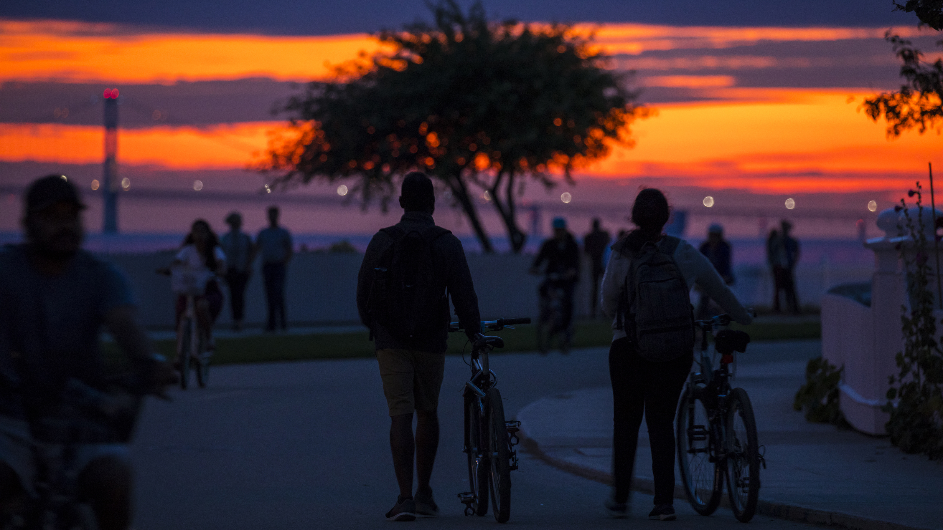 The Mackinac Bridge shines in the distance as the sun sets on Mackinac Island’s boardwalk. Photo courtesy of the Mackinac Island Tourism Bureau.