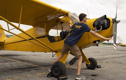 Student pilot Luc Zipkin hand-props a vintage Piper J-3 Cub. Photo by David Tulis.                                                                                                               