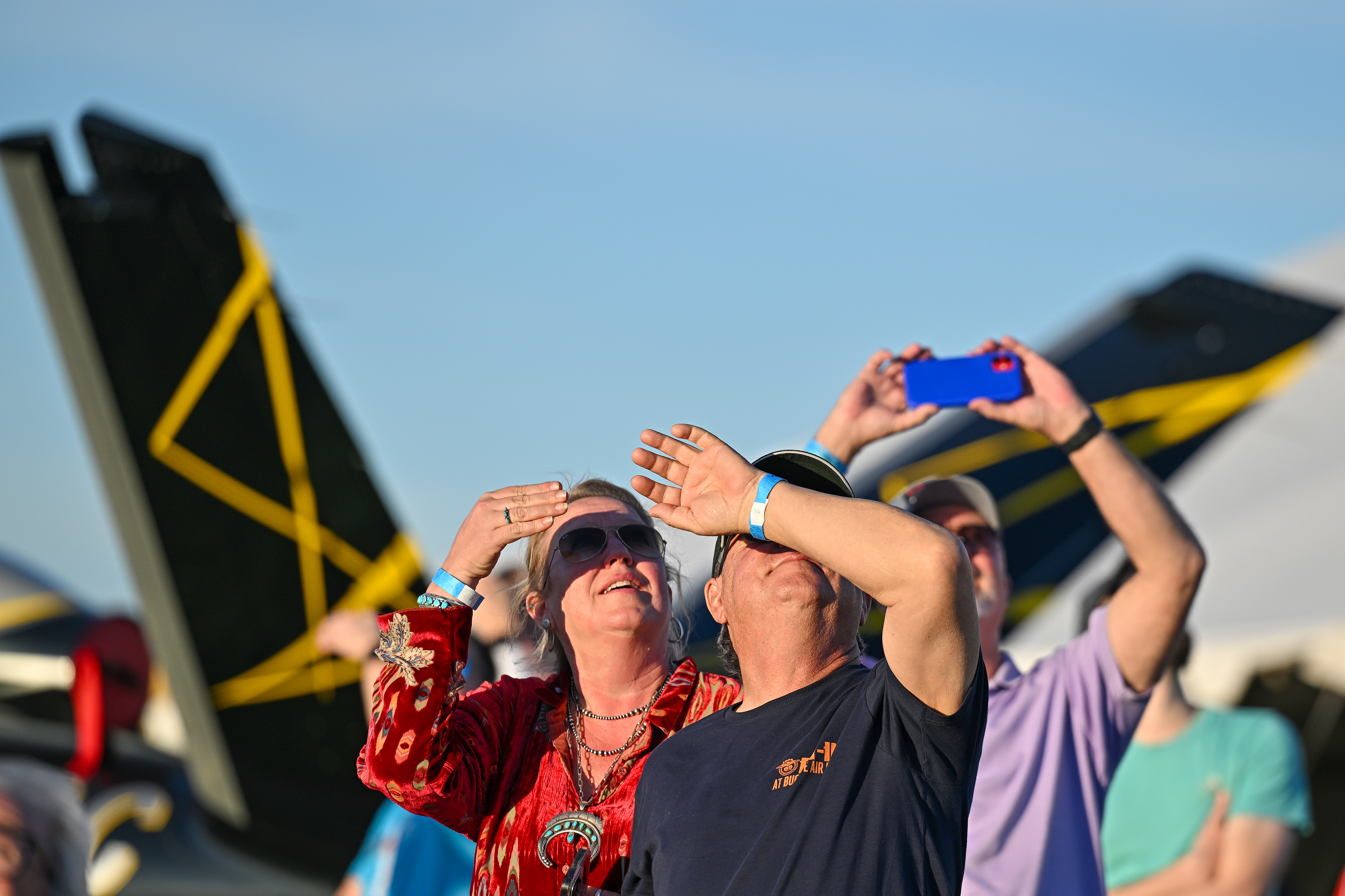 Attendees are framed by the V-tail of a Cirrus SF50 Vision Jet as they watch aerial performances from the AOPA Flightline Chalet. Photo by David Tulis.