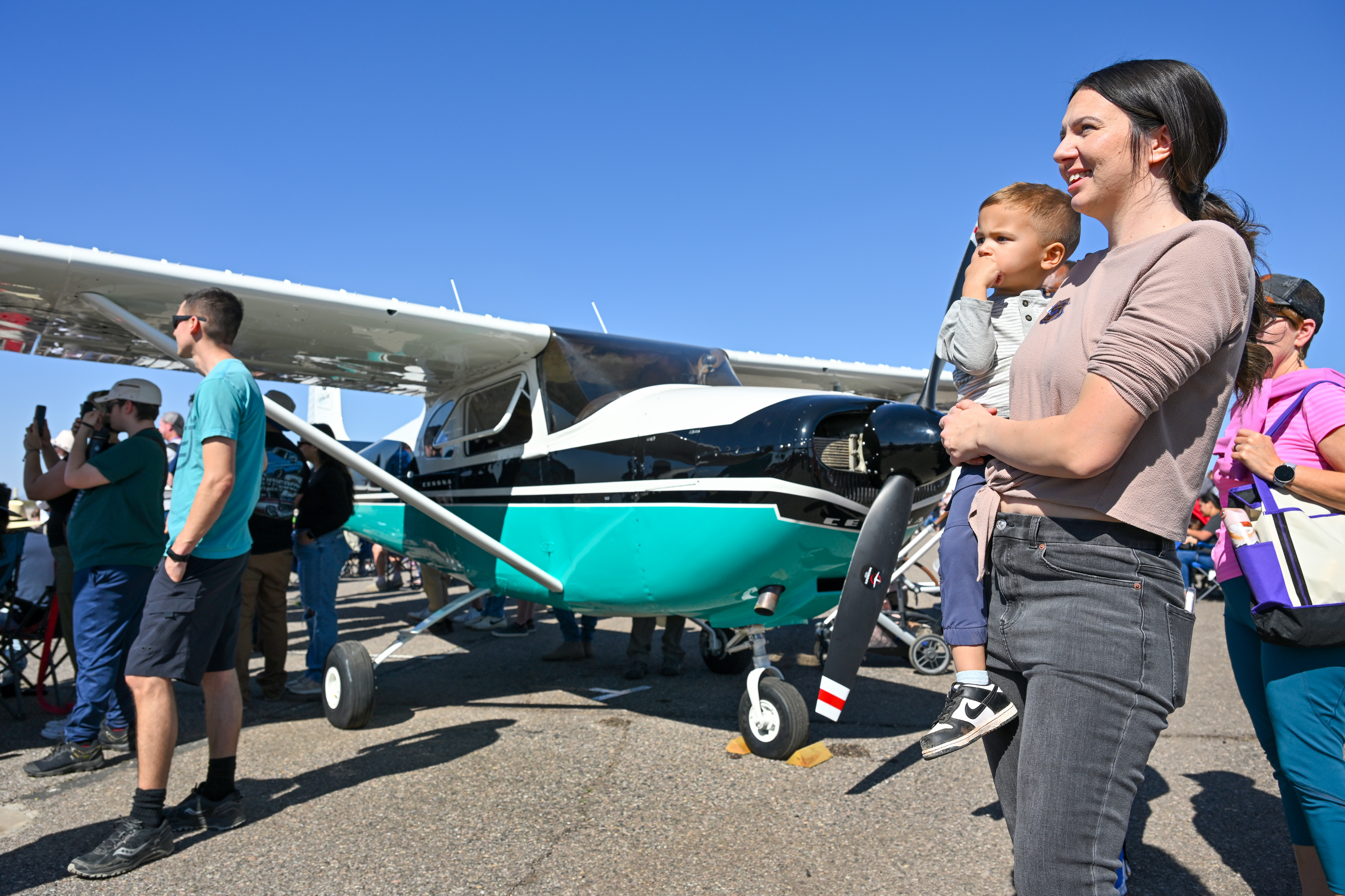 Airshow attendees gather near the AOPA Sweepstakes Cessna 182A to watch aerobatic performers. Photo by David Tulis.