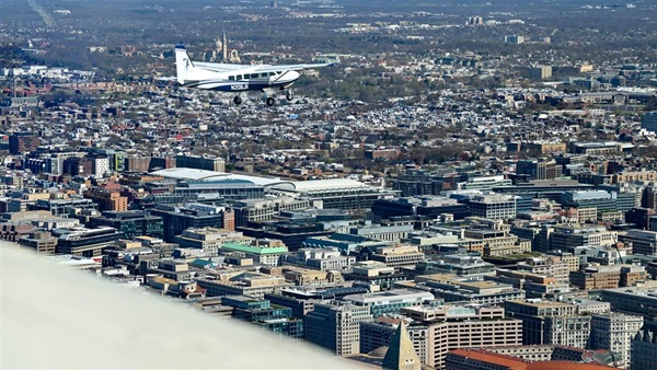 The top of the Washington Monument, lower right, appears below the photo aircraft as AOPA President Mark Baker pilots his Cessna 208 Caravan during a March 24 practice flight for a general aviation flyover of the National Mall in Washington, D.C., to help celebrate AOPA’s eighty-fifth anniversary scheduled for May 11. Photo by David Tulis.