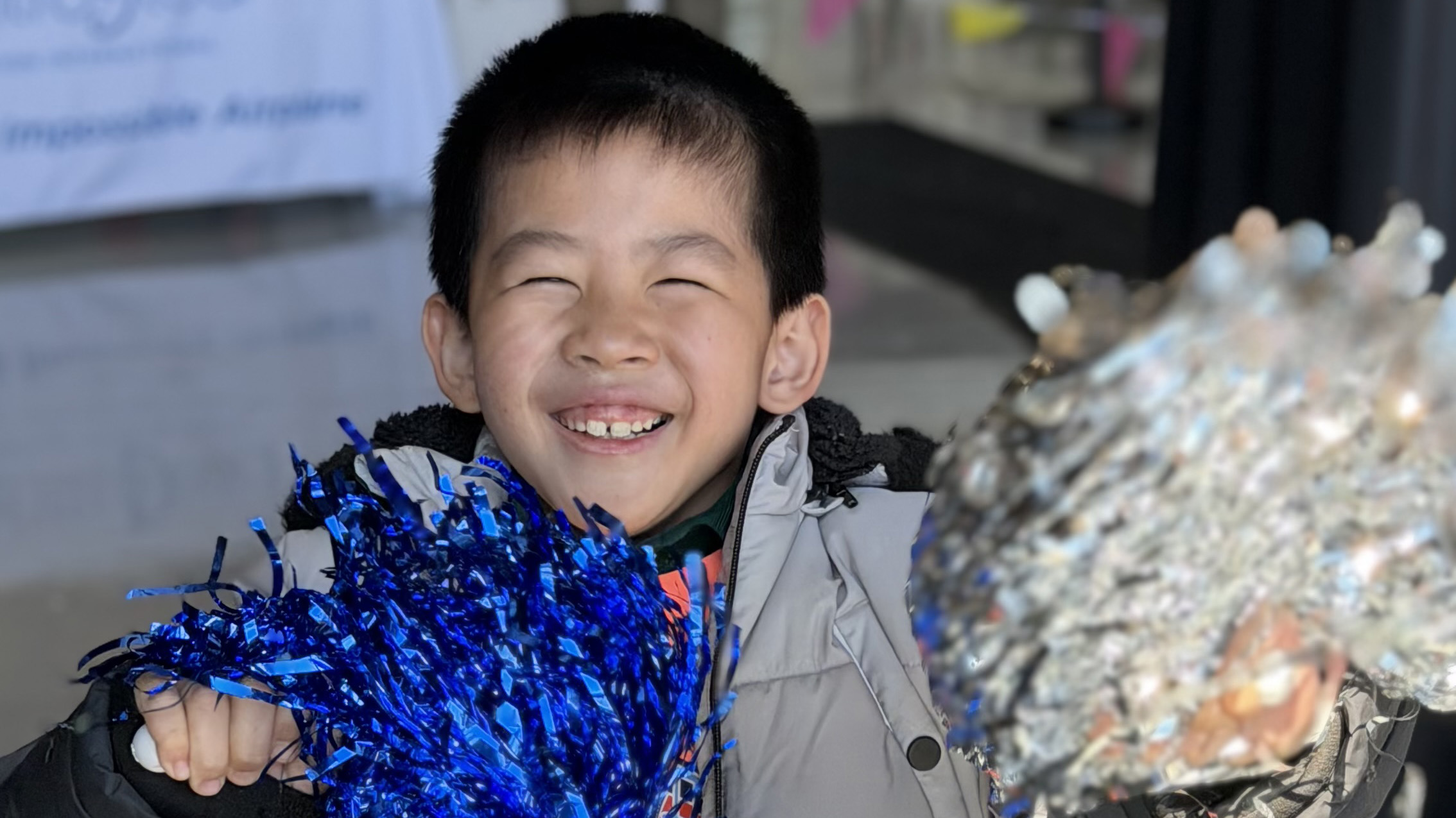 Still elated from his flight, a “co-pilot” shakes the pompoms. Photo by Kari Anderson.