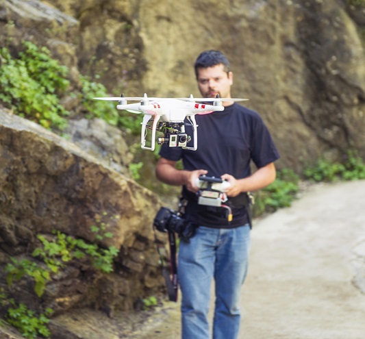 A man uses a handheld controller to fly a DJI Phantom quadcopter. iStock photo.                                                                                                                                                                                                