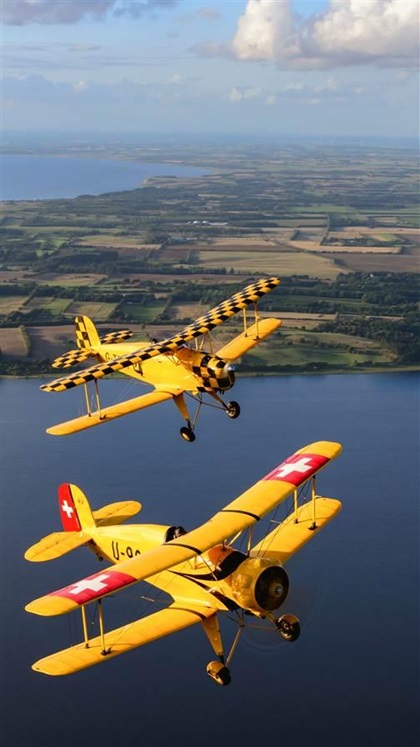 A Bücker Jungmann and Jungmeister flown by Taff Smith and Les Clark of Breighton Aerodrome, Breighton, Selby, United Kingdom, over the Skive Fjord.