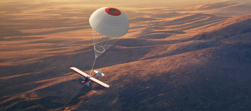 A CubCrafters aircraft floats under a BRS airframe parachute.