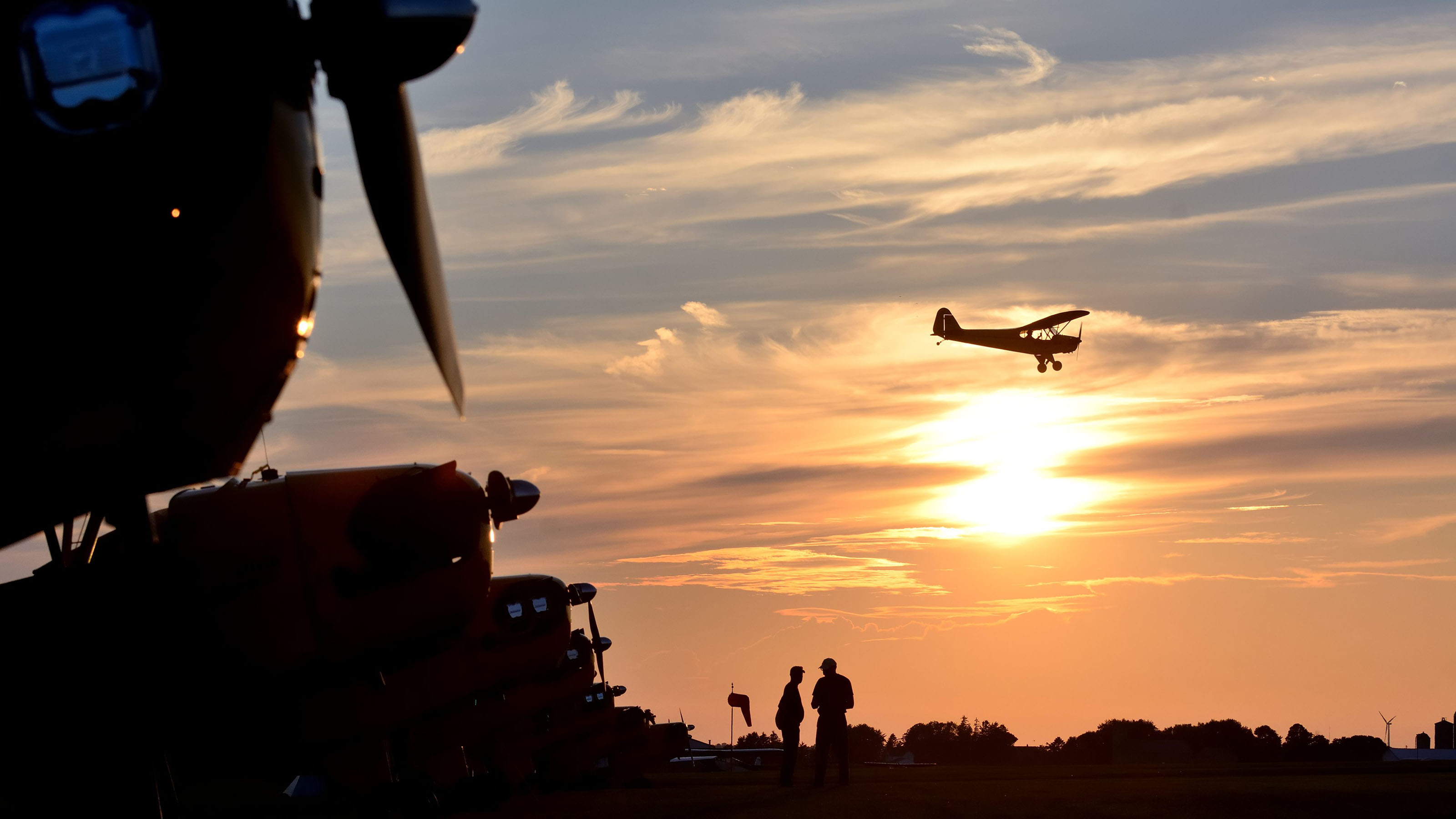 Two Cub pilots talk as another flies the pattern just before sunset.