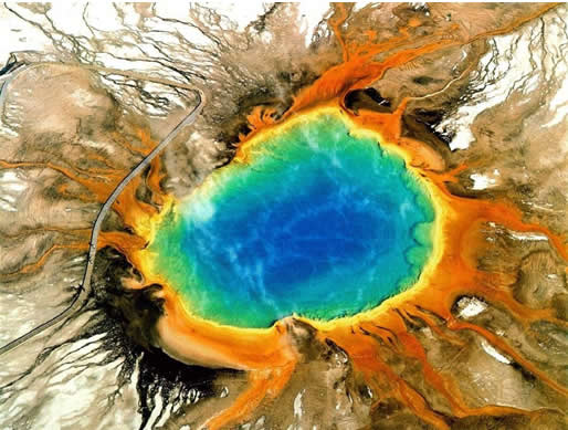 Yellowstone’s Grand Prismatic Spring, a must-see from the air, is the largest hot spring in the U.S. and third-largest in the world, 160 feet deep and with a diameter over 300 feet. The center of the pool is sterile due to the extreme heat. Colors in the mud surrounding the spring are caused by different types of bacteria. Note the people on the boardwalk left of the spring. Photo courtesy Wikipedia.