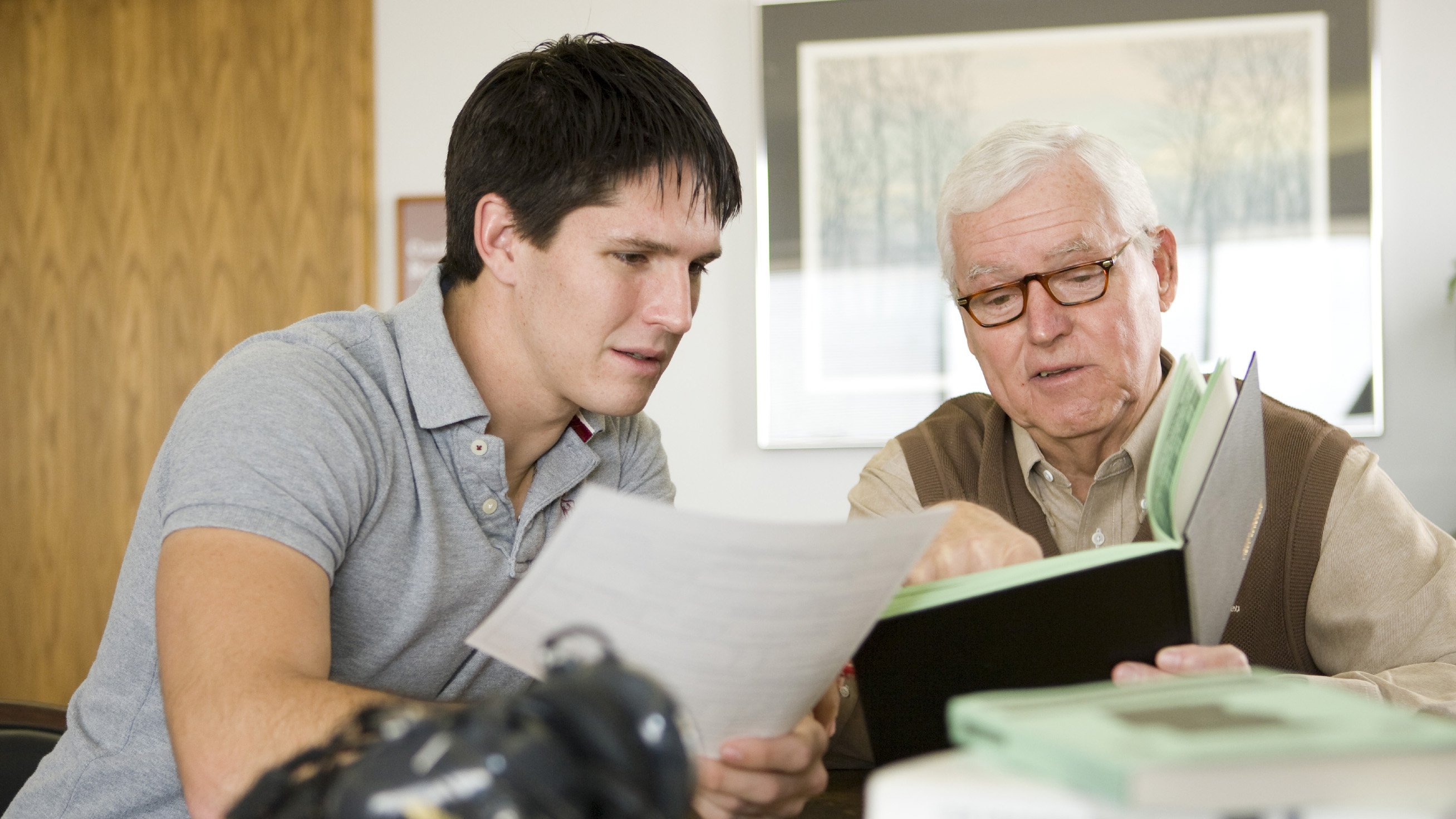 A young student pilot with an older examiner going over the required paperwork prior to the checkride. AOPA file photo by Mike Fizer.