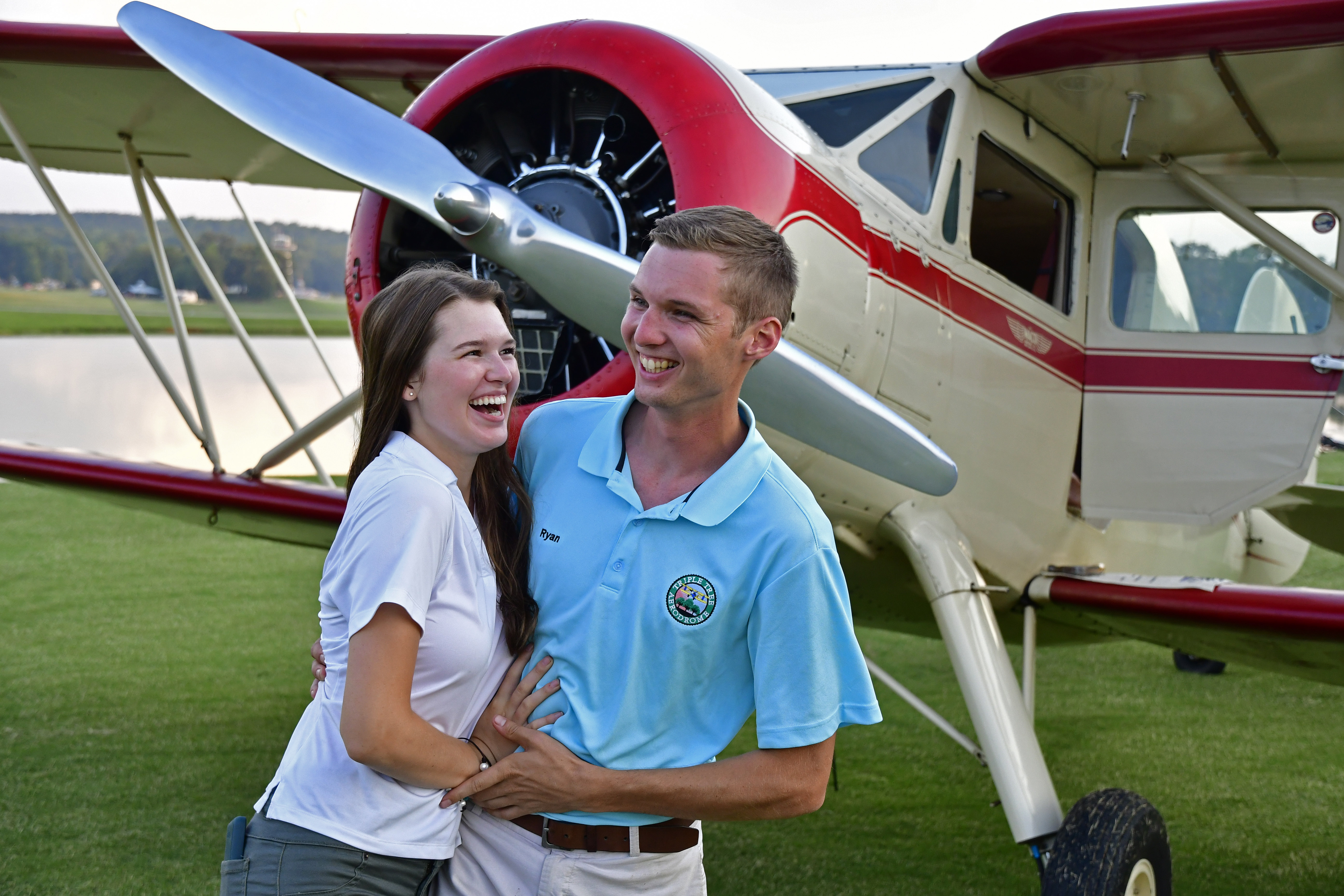 Young Aviators Fly-In organizers Cayla McLeod and Ryan Hunt clown around in front of a cabin Waco YKS-6 biplane at Triple Tree Aerodrome in Woodruff, South Carolina, June 8 to 10. Photo by David Tulis.