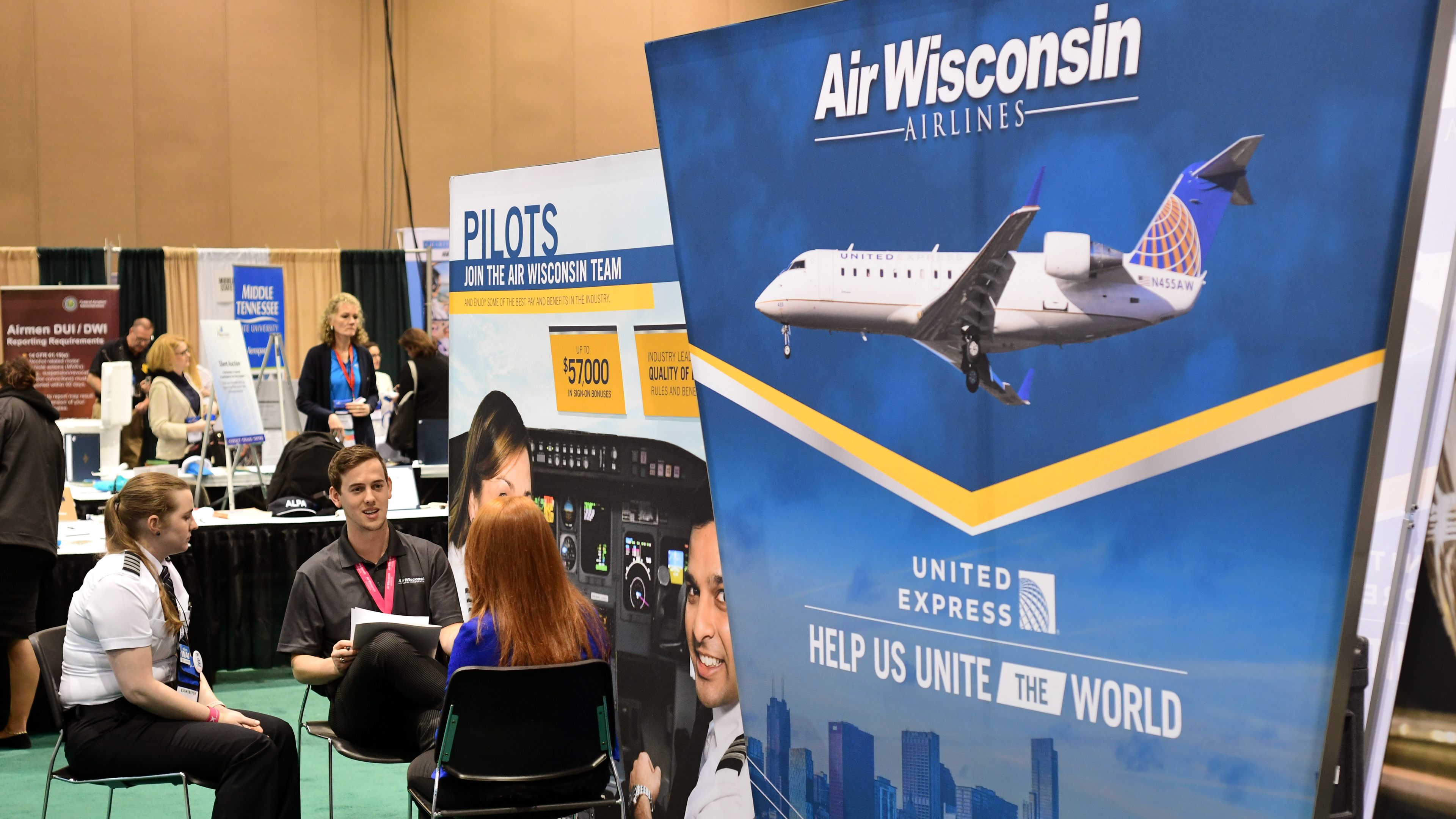 Two Air Wisconsin employees, including a captain (left), interview a pilot applicant behind the company's exhibit booth during the 2018 International Women in Aviation Conference in Reno, Nevada. Photo by Mike Collins.