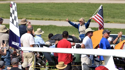From the back of a convertible, airshow pilot Julie Clark interacts with a member of the crowd following one of her performances at EAA AirVenture 2019. Photo by Mike Collins.