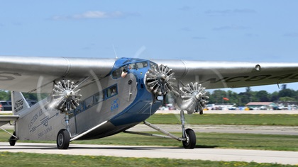 One of EAA's two Ford Tri-Motors taxis south to depart from Runway 36 at EAA AirVenture Oshkosh 2019. Photo by Mike Collins.