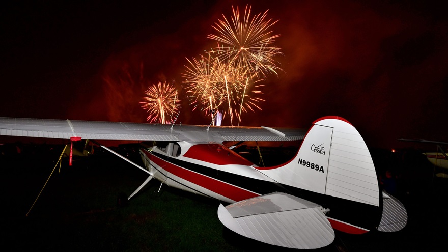 Fireworks arch skyward after the Wednesday night airshow at EAA AirVenture. Bradley Hatcher of Jackson, Georgia, owns the attractive 1950 Cessna 170A in the foreground. Photo by Mike Collins.