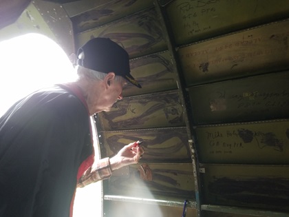 Former C-47 crew chief Franklin Payne autographs the wall of <em>Placid Lassie</em>. Photo by Dan Namowitz.