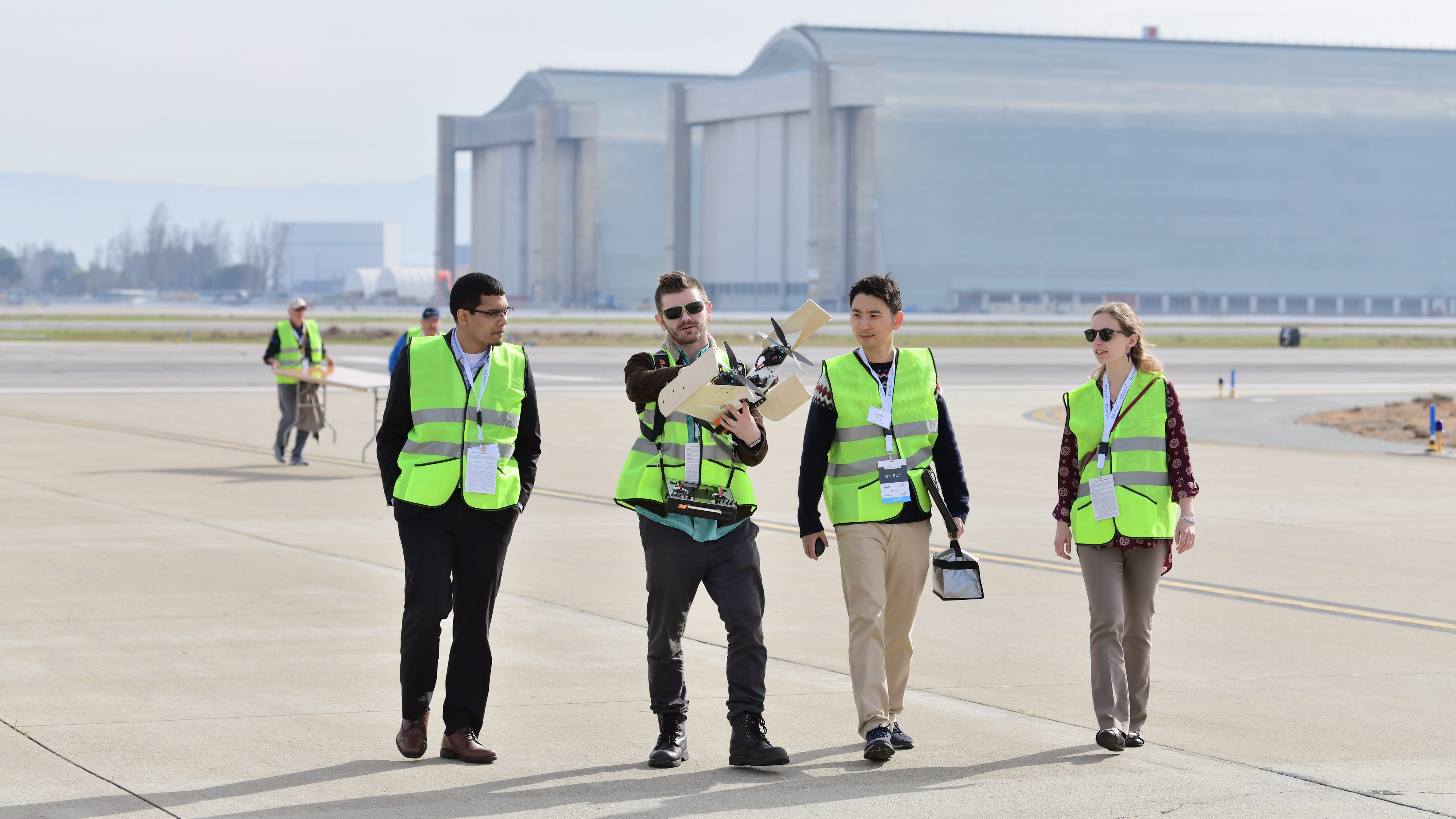 Ben Sena of Team Jayu, second from left, and Soojae Jung, third from left, carry their aircraft at Moffett Federal Airfield after a demonstration flight February 28. Photo by Mike Collins.