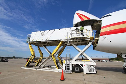 A containerized biocontainment system is moved from a trailer and lifted 18 feet in the air to slide into a Kalitta Air Boeing 747-400 cargo aircraft at Hartsfield-Jackson International Airport in Atlanta. When installed, there is about a 12-inch opening in the aircraft nose between the system and the jet fuselage. Photo courtesy of Phoenix Air.