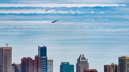 The U.S. Navy Blue Angels and Air Force Thunderbirds fly above the Baltimore skyline. The seagull behind the Blue Angels was not part of the offical formation. Photo by Mike Collins.