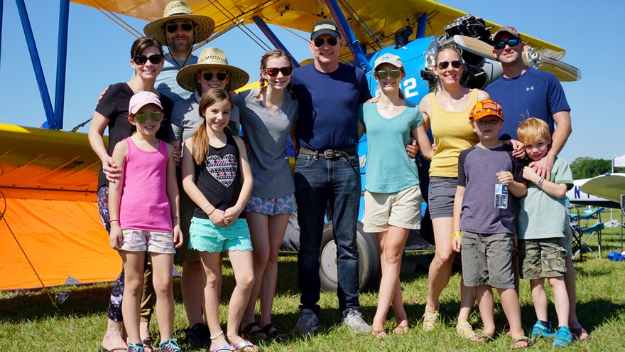 Rick Ferrin's family gathers in front of his Boeing Stearman. The family members are veterans of Sun ‘n Fun. His grandchildren, ages 6 through 13, are most looking forward to their airplane scavenger hunt, watching airplanes, and having quality playtime together. Photo by Cayla McLeod.