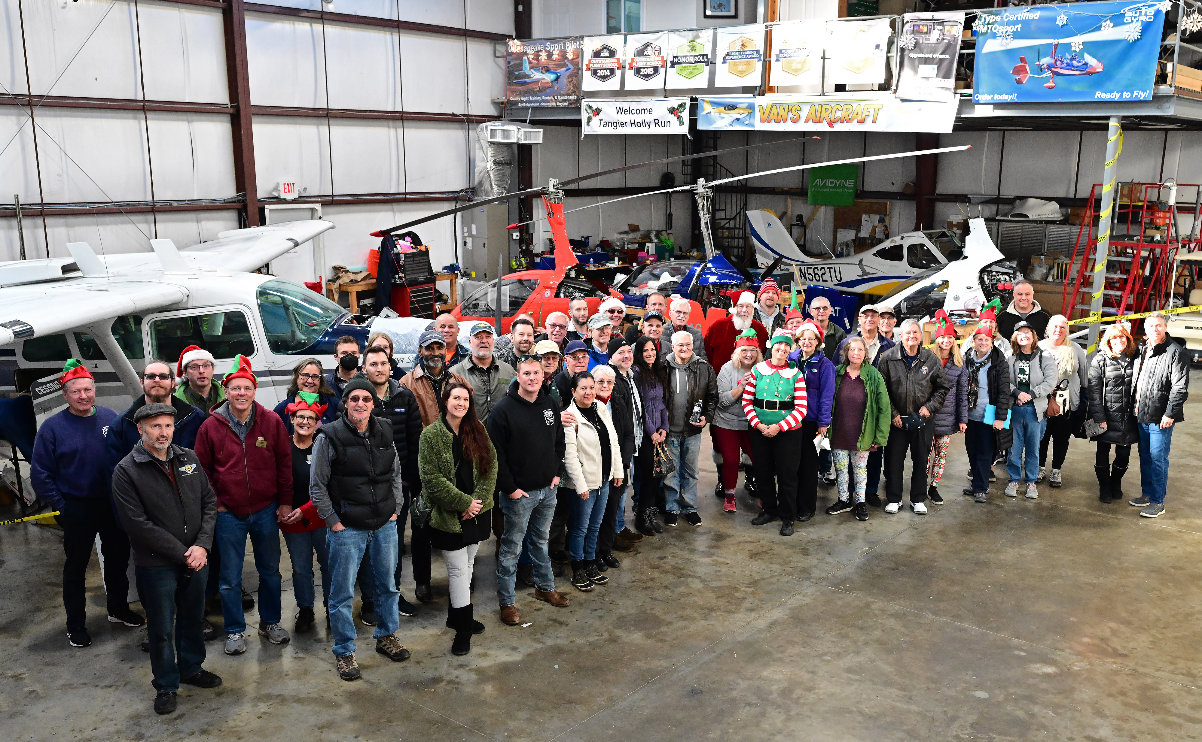 Santa Claus and general aviation pilot Ralph Hoover joins organizer Helen Woods of Chesapeake Sport Pilot and more than 40 aviators for a photo at Bay Bridge Airport in Stevensville, Maryland, before flying to Tangier Island, Virginia, during the annual Holly Run. The charity event was canceled in 2020 because of the coronavirus pandemic. Photo by David Tulis.