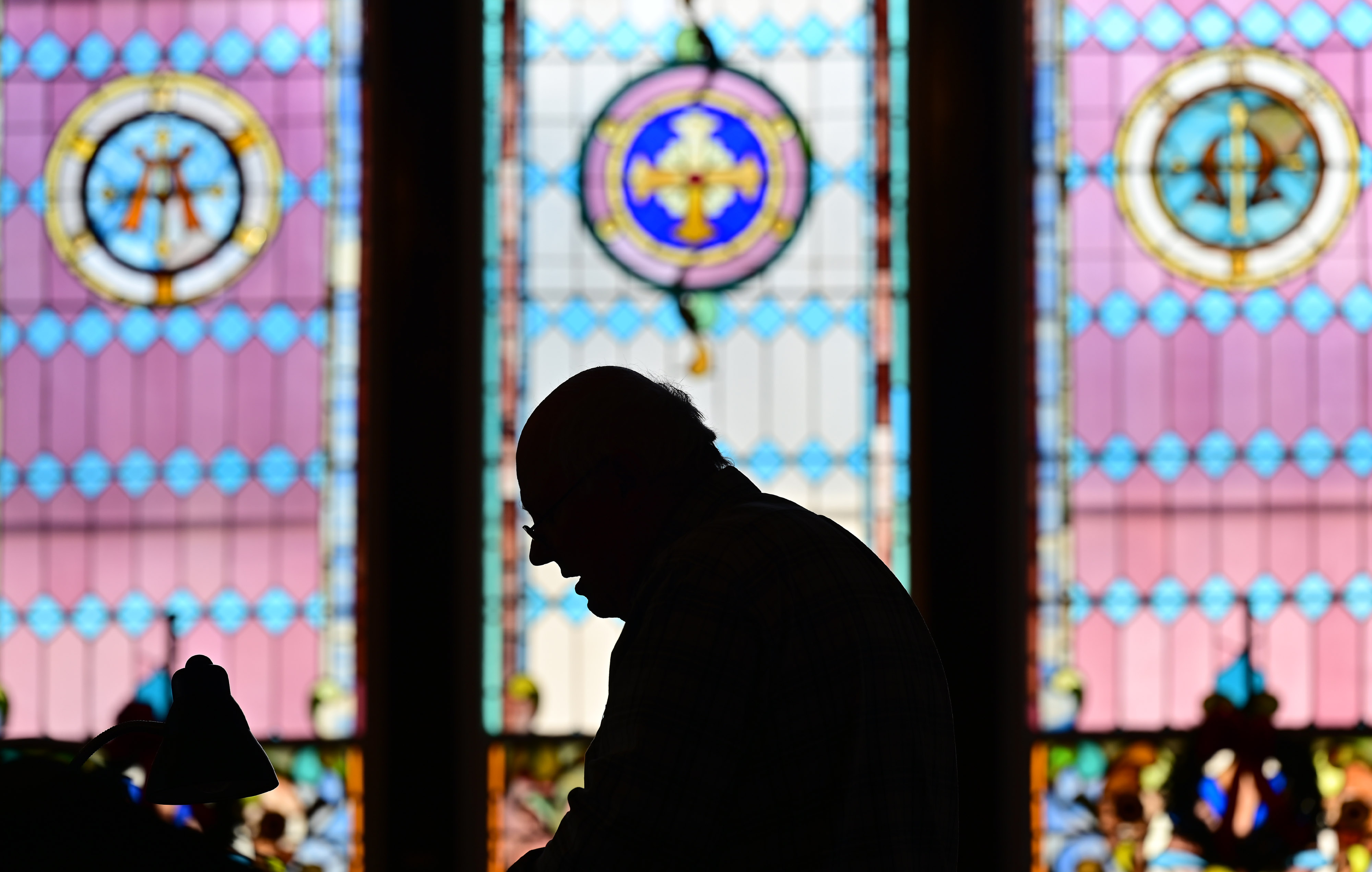 Swain Memorial United Methodist Church’s Denny Crockett is framed by stained glass during a service for pilots donating their time and resources to bring Christmas cheer to Tangier Island, Virginia, in the Chesapeake Bay. Photo by David Tulis.