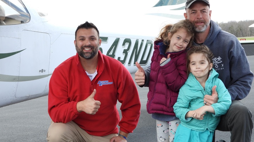 From left, Mike Stenzler flew an airplane while Gordon Landale and his daughters Amelia and Caroline tossed out a bean bag. Photo courtesy Aviation Adventures.