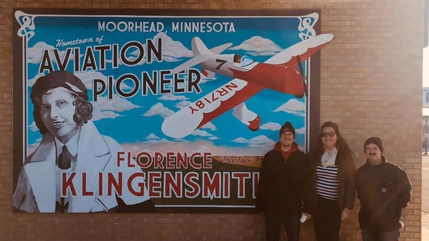 Florence Klingensmith, the first woman pilot licensed in North Dakota, now has a mural in her likeness as well as an airport named after her. Shown with the mural left to right are Jared Froeber, Marisa Bengtson-Loerzel, and Cory Gillerstein. Froeber and Gillerstein created the mural, and Bengtson-Loerzel led efforts to rename the airport after Klingensmith. Photo courtesy of Marisa Bengtson-Loerzel.