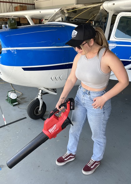 The author uses the Milwaukee handheld blower to clean out sand and debris from her hangar. Photo courtesy of Niki Britton.