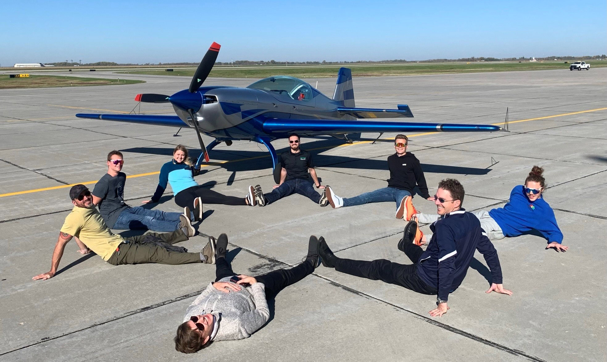 Clockwise from far left: Pilot Shaun Brautigan and University of North Dakota aviation students Shawn Higgins, Mikaila Gillis, Jon DeLone, Christoph Webber, Andrew Coughlin, Mike Lents, and Ben Stassen sit in front of the Extra NG during Brautigan and Angela Rogers' cross-country flight. Photo courtesy of Shaun Brautigan.