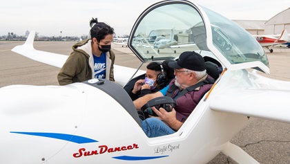 New Vision student Johnathan Alvarado helps Adam Arenas settle into the Distar SunDancer for an intro flight with Michael Tomazin. Photo by Niki Britton.