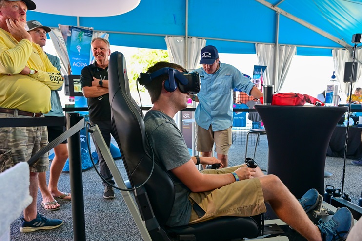Attendees take turns flying in virtual reality at the AOPA campus during EAA AirVenture Oshkosh July 25. Photo by David Tulis.